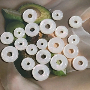 Close-up of iridescent faux mop opal donut charms for DIY jewelry making in various sizes