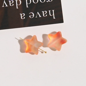 Macro view of matte gradient star beads in peach pink with gold metal pin detail