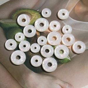 Close-up of iridescent pearlescent round donut charms in various sizes for DIY jewelry