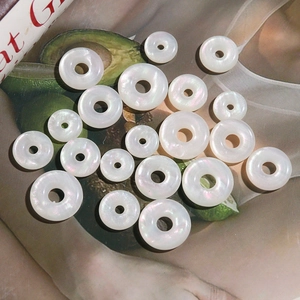 Flat lay of iridescent faux shell doughnut beads for DIY jewelry making and earrings