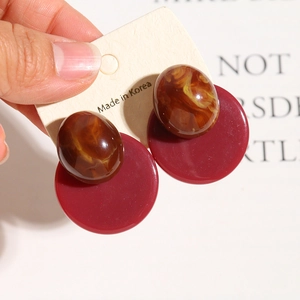 Close-up of vintage resin earrings with brown marble texture and burgundy round base