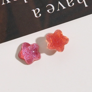 Glitter star resin earrings in purple and pink displayed on a monochrome background