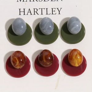 Close-up of Morandi resin earring components in deep green and burgundy marble tones