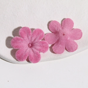 Gros plan de breloques fleurs floquées roses pour la création de bijoux artisanaux