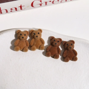 Makroaufnahme brauner beflockter Minibären für DIY-Schmuck auf einer Keramikplatte