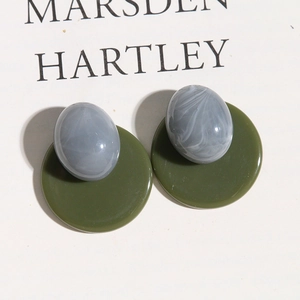 Macro detail of retro oval earrings with marble texture on an olive green base