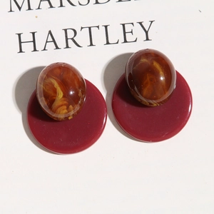 Close-up of vintage Morandi-style oval resin earrings with deep red round base