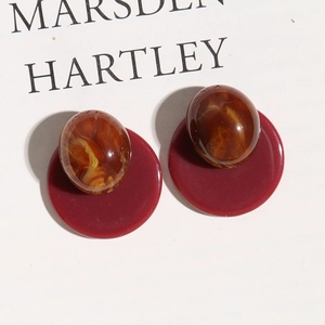 Detail view of oval marble-textured beads on dark red round resin earring bases