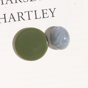 Close-up of matte army green resin disc and marbled oval beads for DIY jewelry making