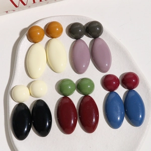 Macro view of Morandi resin earrings with oval and spherical designs on ceramic plate