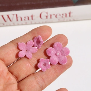 Detailed view of pink flocked lily of the valley charms held in hand for DIY jewelry
