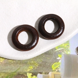 Close-up of dark brown wooden circular rings for DIY earrings on a white surface