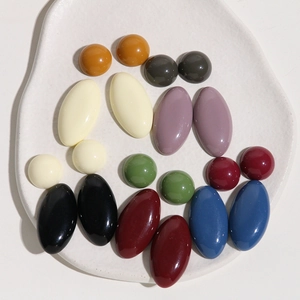 Flat lay of oval and round Morandi resin pieces for DIY jewelry on ceramic tray