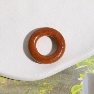 Macro shot of polished brown wooden circular charm with natural grain texture on tray