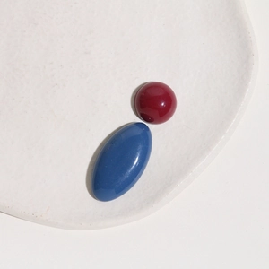Macro shot of glossy Morandi red round and blue oval resin cabochons on a white tray