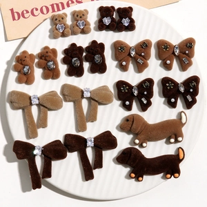 Detail of flocked animal charms with rhinestones and pearls on a white textured tray