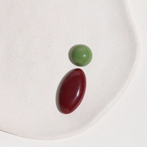 Close-up of glossy oval resin cabochons in olive green and burgundy colors