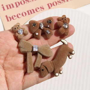 Close-up of brown flocked bear and dog DIY charms with rhinestones and white pearls