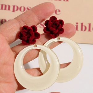 Eleganti orecchini a rosa rossa con cerchi in resina bianco sporco mostrati a mano