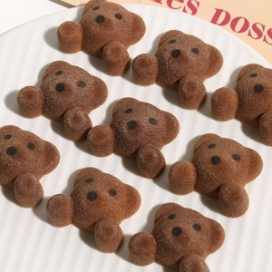 Macro detail of cute brown flocked bear resin accessories arranged on a white ceramic plate