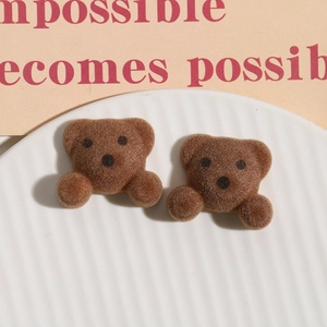 Close-up of brown flocked bear charms for DIY hair accessories on a white ceramic plate