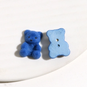 Detail van blauwe geflokte berenbedeltjes met textuur en gaten voor DIY-sieraden maken