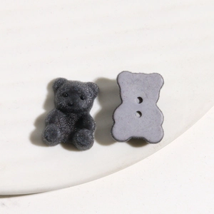 Macro-opname van donkergrijze gevlokte berenbedeltjes en knopen voor DIY-haaraccessoires