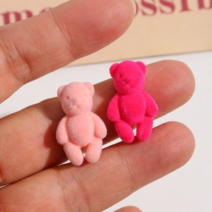 Close-up of mini flocked teddy bear charms in pink and rose for DIY jewelry and nail art