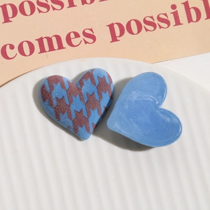 Macro detail of houndstooth heart and marble blue charms on a textured tray