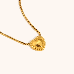 Close-up of golden heart pendant necklace with twisted rope edge and box chain detail