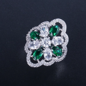 Detailed macro view of silver flower ring with green emerald-cut cubic zirconia and diamonds