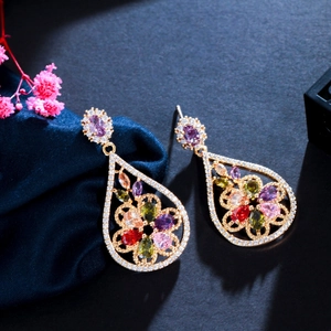 Detailed shot of gold plated drop earrings with colorful zircon stones on silk background