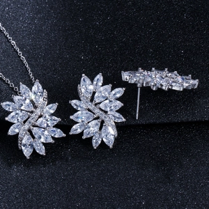 Macro detail of silver necklace and marquise zircon stud earrings set on black background