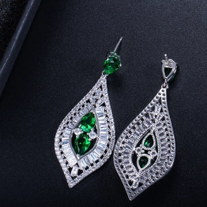 Primer plano de pendientes bohemios con piedras verde esmeralda y circonitas blancas