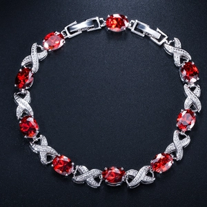 Detail view of oval ruby-red stones and pavé set crystals on a silver-plated luxury bracelet