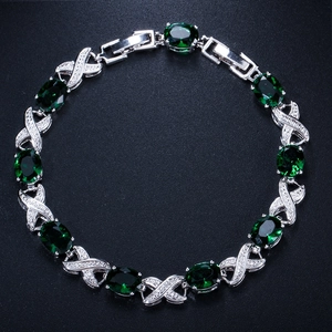 Detailed macro of silver bracelet with eight oval green stones and X-shaped crystal links