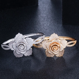 Macro shot of sparkling zircon-encrusted gold and silver flower open bangles on black