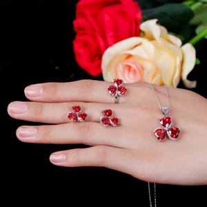 Three-piece jewelry set with red heart-shaped stones in a floral clover design