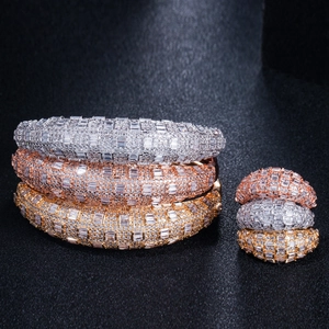 Dettaglio di bracciali rigidi larghi e anelli con micro-pavé di zirconi cubici