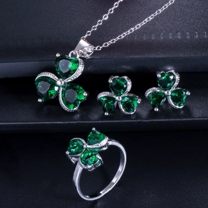 Macro detail of silver clover jewelry set featuring deep green zircon stones