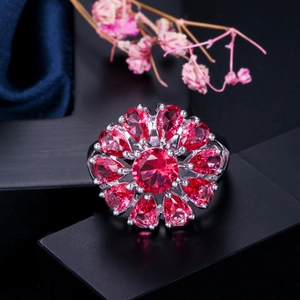 Primer plano de un anillo floral con circonitas rojo rubí y una banda de metal en tono plateado