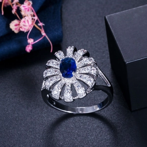 Elegant flower ring featuring deep blue oval gemstone and micro-pave zircon petals
