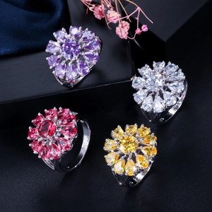 Detalle de anillos en forma de flor con circonitas AAA de colores sobre seda oscura