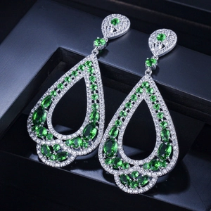 Détail de boucles d'oreilles goutte de luxe avec pierres vert émeraude et pavé de zircons