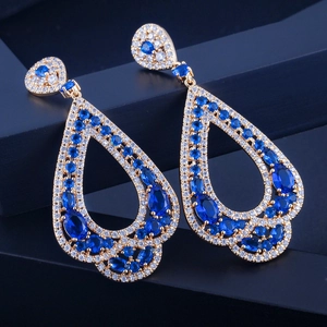 Gros plan sur des boucles d'oreilles dorées avec zircons AAA bleus et blancs