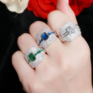Drie brede ringen met smaragd, saffier en zirkoonstenen op een zwarte bloemenachtergrond