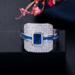 Macro-opname van luxe ring met rechthoekige blauwe saffier en witte zirkonia-steentjes