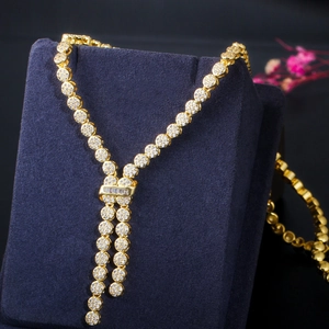 Close-up of golden Y-shaped tassel necklace with cubic zirconia on velvet stand