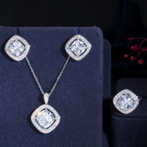 Macro shot of silver jewelry set with square zircon pendants on blue velvet