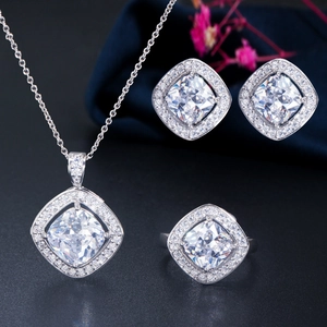 Detailed view of square-cut halo jewelry set with necklace earrings and ring on blue silk